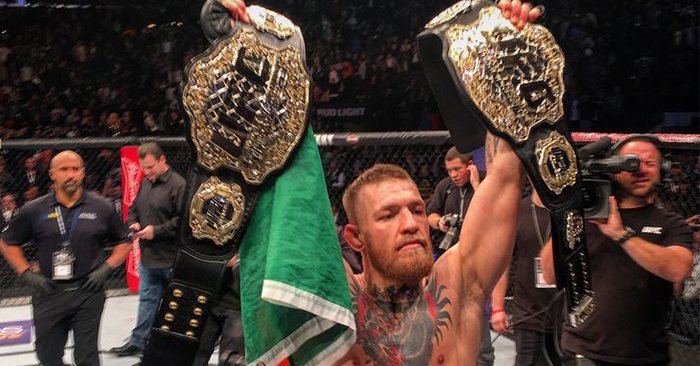 UFC superstar Conor McGregor with two UFC titles in the air.